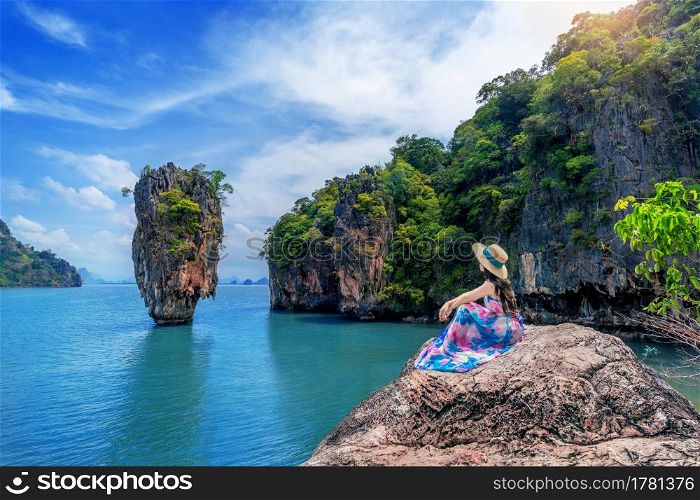 Beautiful girl sitting on the rock at James Bond island in Phang nga, Thailand.