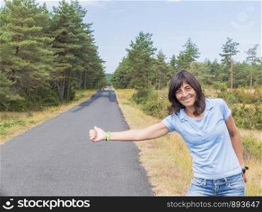 Beautiful girl standing on a highway and catching a passing car.