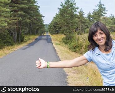 Beautiful girl standing on a highway and catching a passing car.