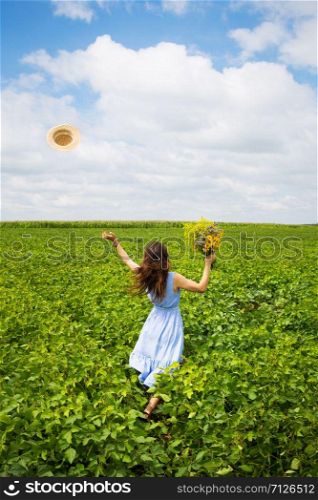 beautiful girl stands in the field with a bouquet of yellow flowers and throws her hat to the sky.. beautiful girl stands in the field with a bouquet of yellow flowers and throws her hat to the sky