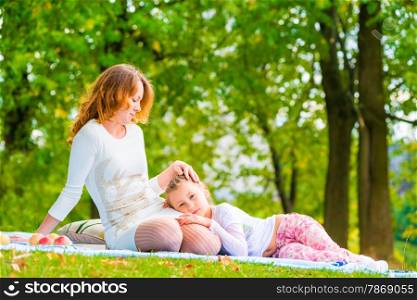 beautiful girl stroking her daughter on the lawn in the park