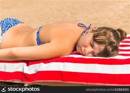 beautiful girl sunbathes on a beach in a lounge chair