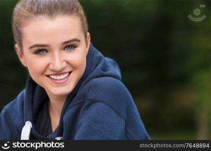 Beautiful girl teenager female young woman with blue eyes outside wearing dark blue hoodie happy and smiling with perfect teeth