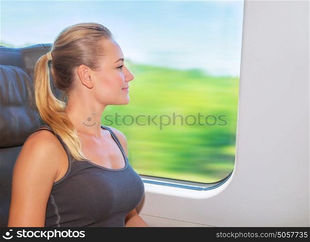 Beautiful girl traveling on the train in first class, looking to window, having fun, enjoying beautiful view, summertime vacation in Europe