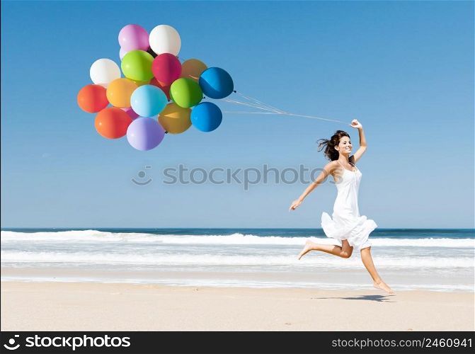 Beautiful girl walking in the beach while holding colored balloons