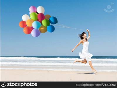 Beautiful girl walking in the beach while holding colored balloons