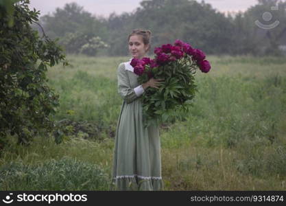 beautiful girl with a bouquet of peonies in the garden 