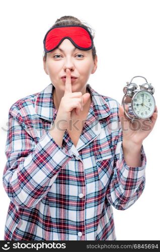 "Beautiful girl with a lip gesture "QUIET" holds an alarm clock i. Beautiful girl with a lip gesture "QUIET" holds an alarm clock in the evening on a white background"