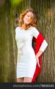 beautiful girl with curly hair on the background of a tree trunk