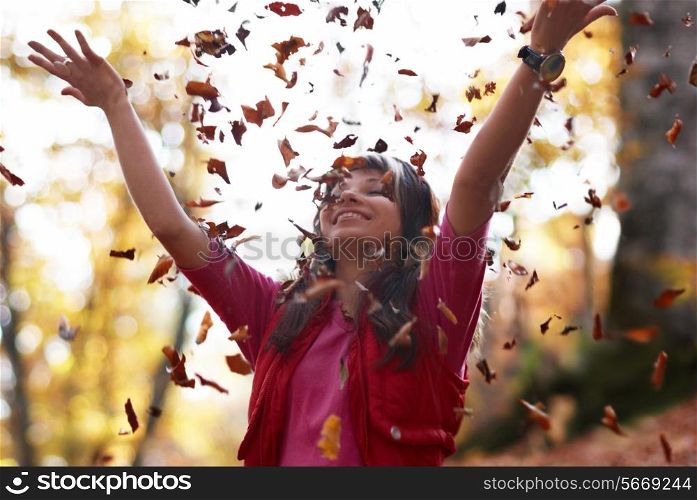 Beautiful girl with falling leaves in the autumn park