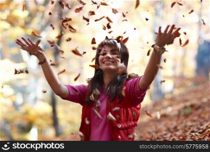 Beautiful girl with falling leaves in the autumn park