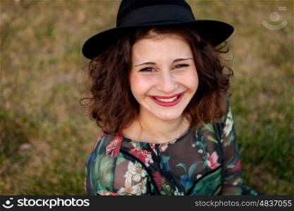 Beautiful girl with flowered dress an black hat in the landscape