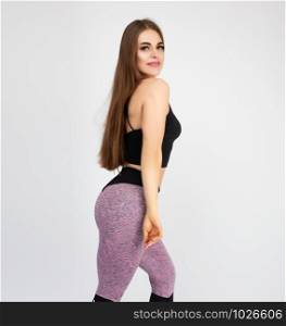 beautiful girl with long hair and a sports figure posing on a white background, wearing a black sconce and colored leggings
