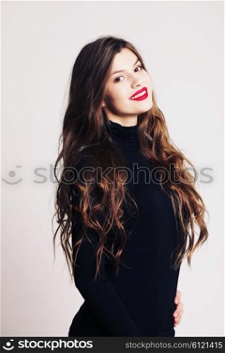 Beautiful girl with long wavy healthy hair. Brunette with curly hairstyle, and professional makeup, red lips.