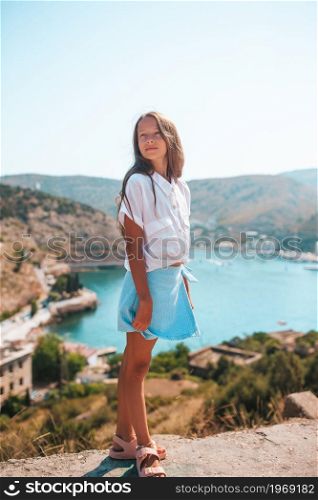 Beautiful girl with overlooking the bay. Little girl on top of a mountain enjoying valley view