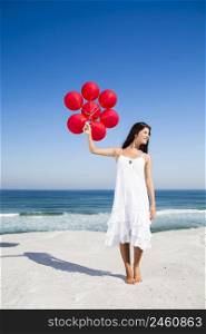 Beautiful girl with red ballons in the beach