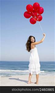 Beautiful girl with red ballons in the beach
