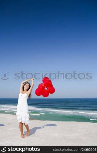 Beautiful girl with red ballons in the beach