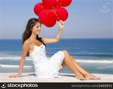 Beautiful girl with red ballons sitting in the beach