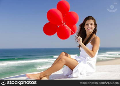 Beautiful girl with red ballons sitting in the beach