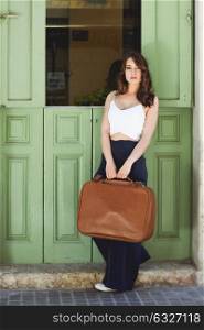 Beautiful girl with vintage bag against green door in urban background. Casual spring clothes