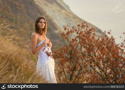 Beautiful girl with wild flowers on the background of a beautiful landscape