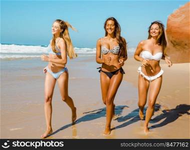 Beautiful girls enjoying the summer,  running on the beach 