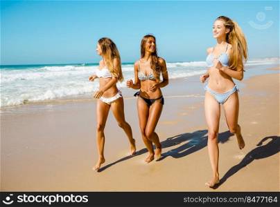 Beautiful girls enjoying the summer,  running on the beach 