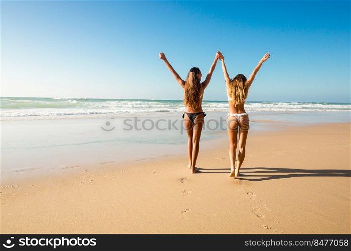 Beautiful girls in bikin walking on the beach
