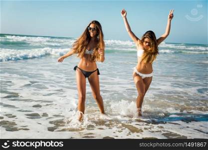 Beautiful girls in the beach having fun on the water