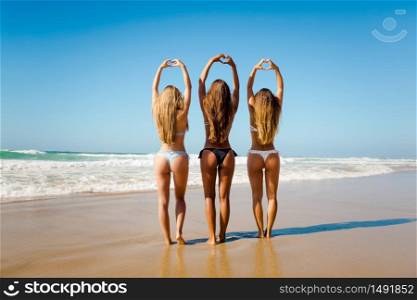 Beautiful girls in the beach making hearts with their hands