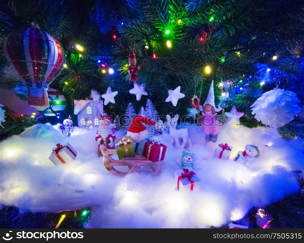 Beautiful glowing christmas tree with many present boxes and decor on snow. Christmas decor under the tree