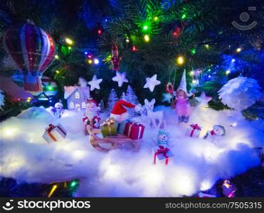Beautiful glowing christmas tree with many present boxes and decor on snow. Christmas decor under the tree