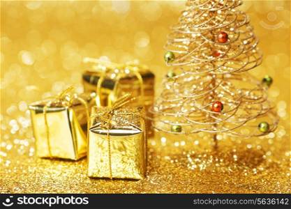 Beautiful golden decorative christmas tree and gifts on golden glitter background