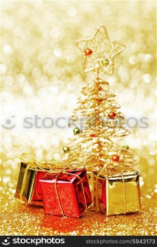 Beautiful golden decorative christmas tree and gifts on golden glitter background