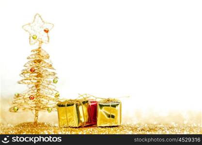 Beautiful golden decorative christmas tree and gifts on golden glitter background with white copy space