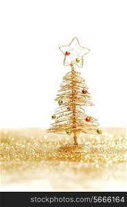 Beautiful golden decorative christmas tree on golden glitter background with white copy space