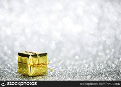 Beautiful golden small holiday gift box on silver glitters
