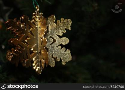Beautiful golden snowflake ornament hanging on the Christmas tree.