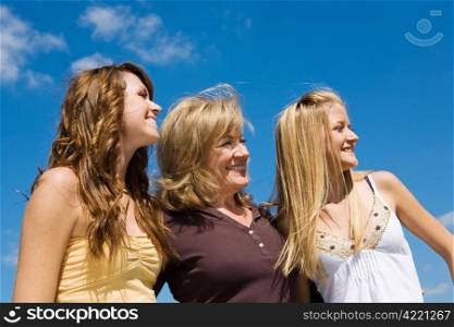 Beautiful grandmother & granddaughters laughing in profile against a blue sky.
