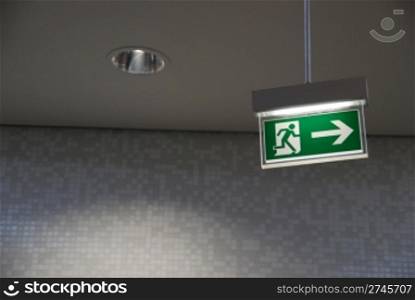 beautiful green emergency exit sign hanging on a ceiling