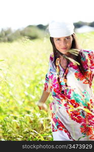 Beautiful gypsy girl with scarf standing in meadow