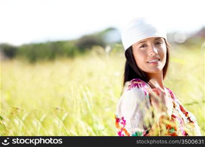 Beautiful gypsy girl with scarf standing in meadow