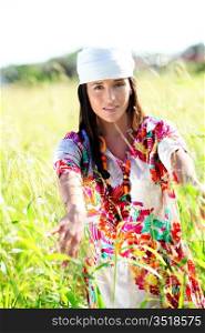 Beautiful gypsy girl with scarf standing in meadow