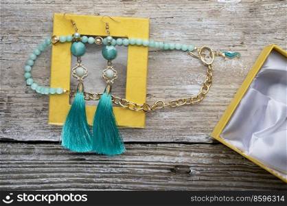 beautiful handmade  turquoise  jewelry with natural gems in yellow box around old style wooden background. close up. fashion concept