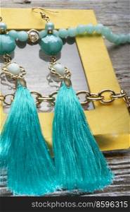 beautiful handmade  turquoise  jewelry with natural gems in yellow box around old style wooden background. macro shot. fashion concept