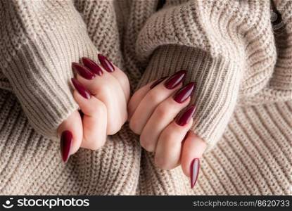 Beautiful hands of a young woman with dark red manicure on nails. Autumn winter nail design concept of beauty treatment.