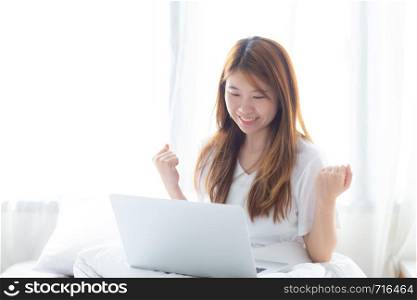 Beautiful happiness young asian woman using laptop work with success on bed in the home, girl and notebook shopping online with glad, communication concept.