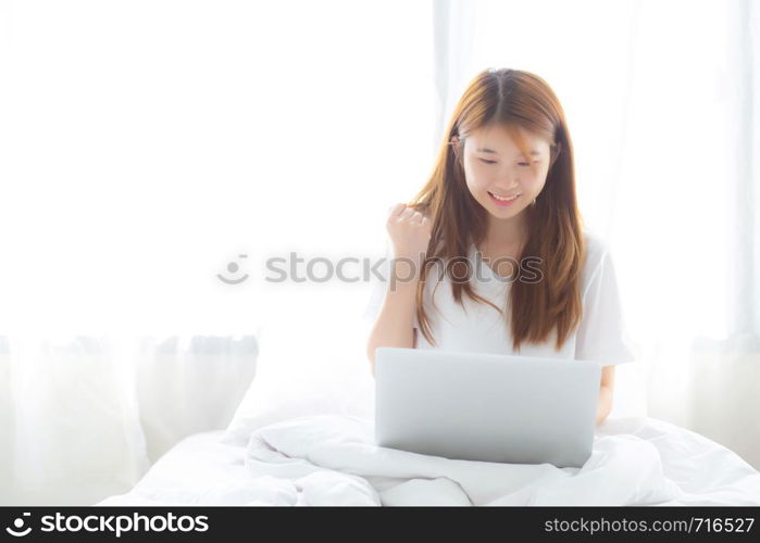 Beautiful happiness young asian woman using laptop work with success on bed in the home, girl and notebook shopping online with glad, communication concept.