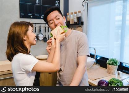 Beautiful happy asian couple are feeding each other in the kitch. Beautiful happy asian couple are feeding each other in the kitchen. Young asian man and woman have romantic time while staying at home. Couple lifestyle at home concept.